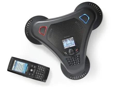 A triangular conference call speakerphone beside a handset.