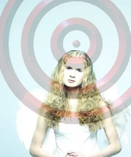 A girl standing in front of a large concentric target.